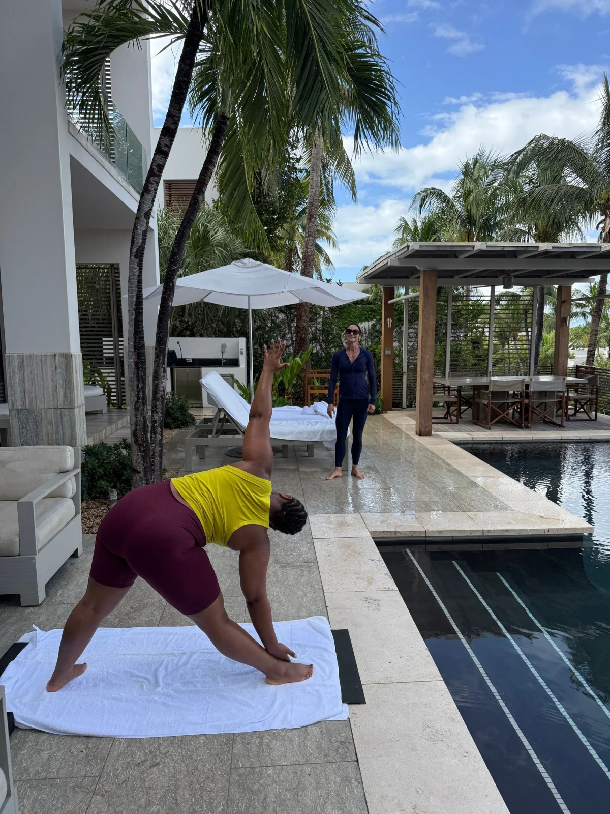 Image may contain adult woman doing yoga with a teacher beside a pool