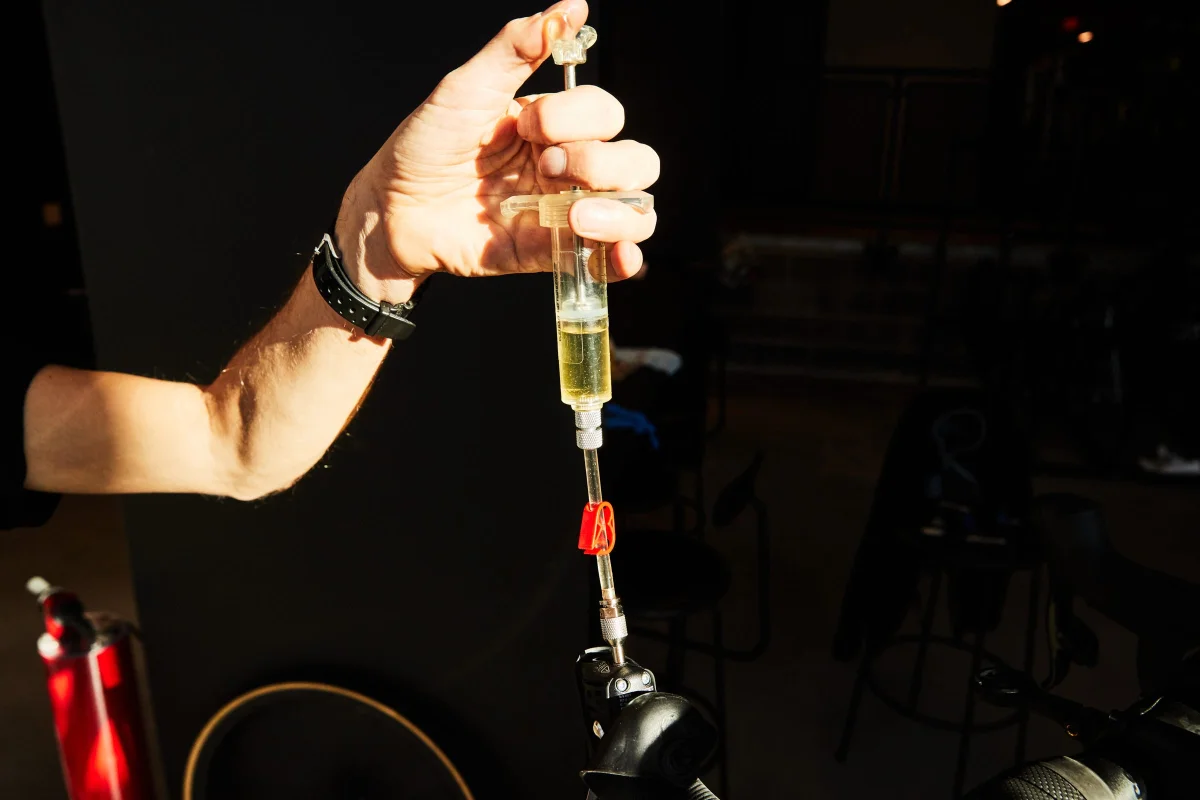 A person using a syringe to inject oil into a bicycle component. A person using a syringe to inject oil into a bicycle component.